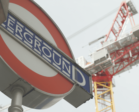 Tower crane behind an underground sign in London